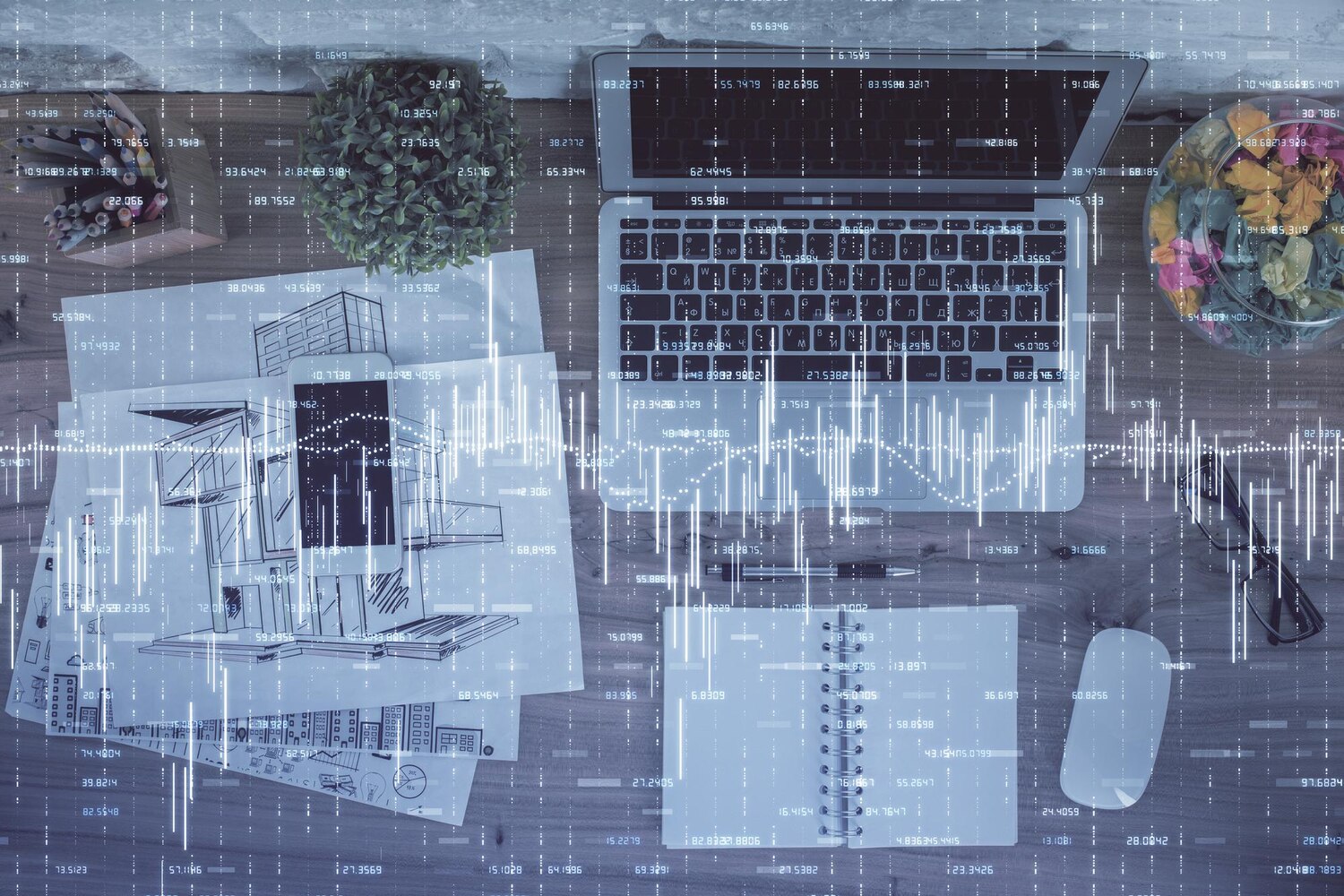 Felülnézet egy íróasztalról, laptop, tervrajzok, jegyzetfüzet és egér látható, átlátszó pénzügyi grafikonokkal. A skeleton-módszer, írj jobb AI cikkeket vázlatból