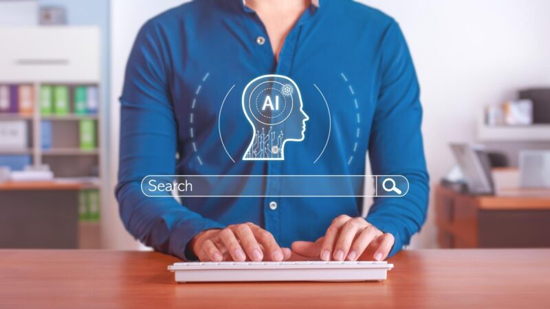Férfi gépel billentyűzeten, felette mesterséges intelligencia (AI) ikon és keresőmező. SEO és AI témájú illusztráció.