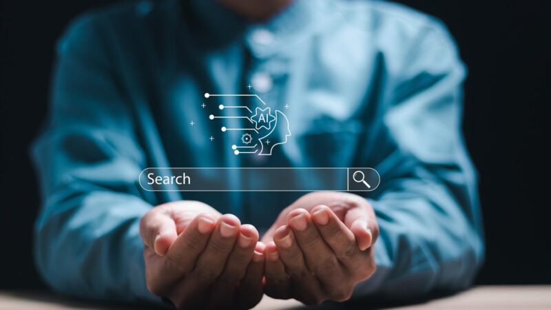Nyitott tenyéren lebegő keresőmező és mesterséges intelligencia (AI) ikon, ami a Google AI változásokat szimbolizálja.