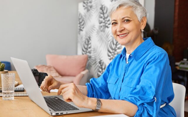 Mosolygó szakértő nő laptopon dolgozik az otthoni irodájában