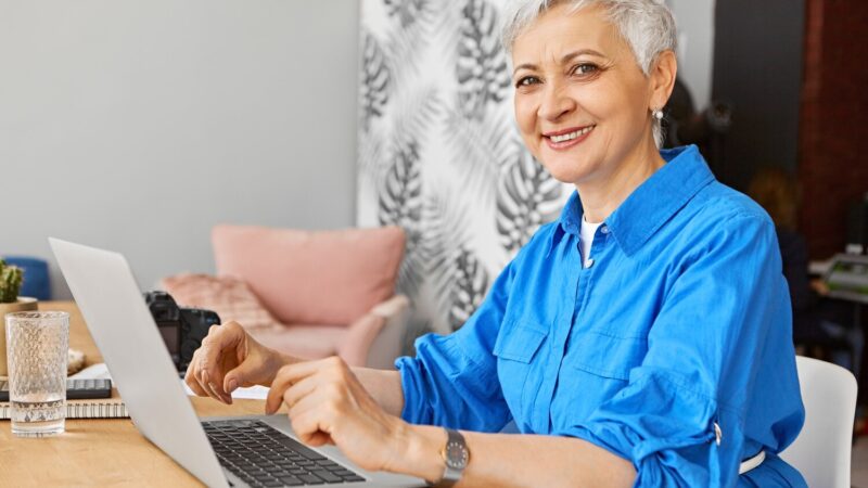 Mosolygó szakértő nő laptopon dolgozik az otthoni irodájában