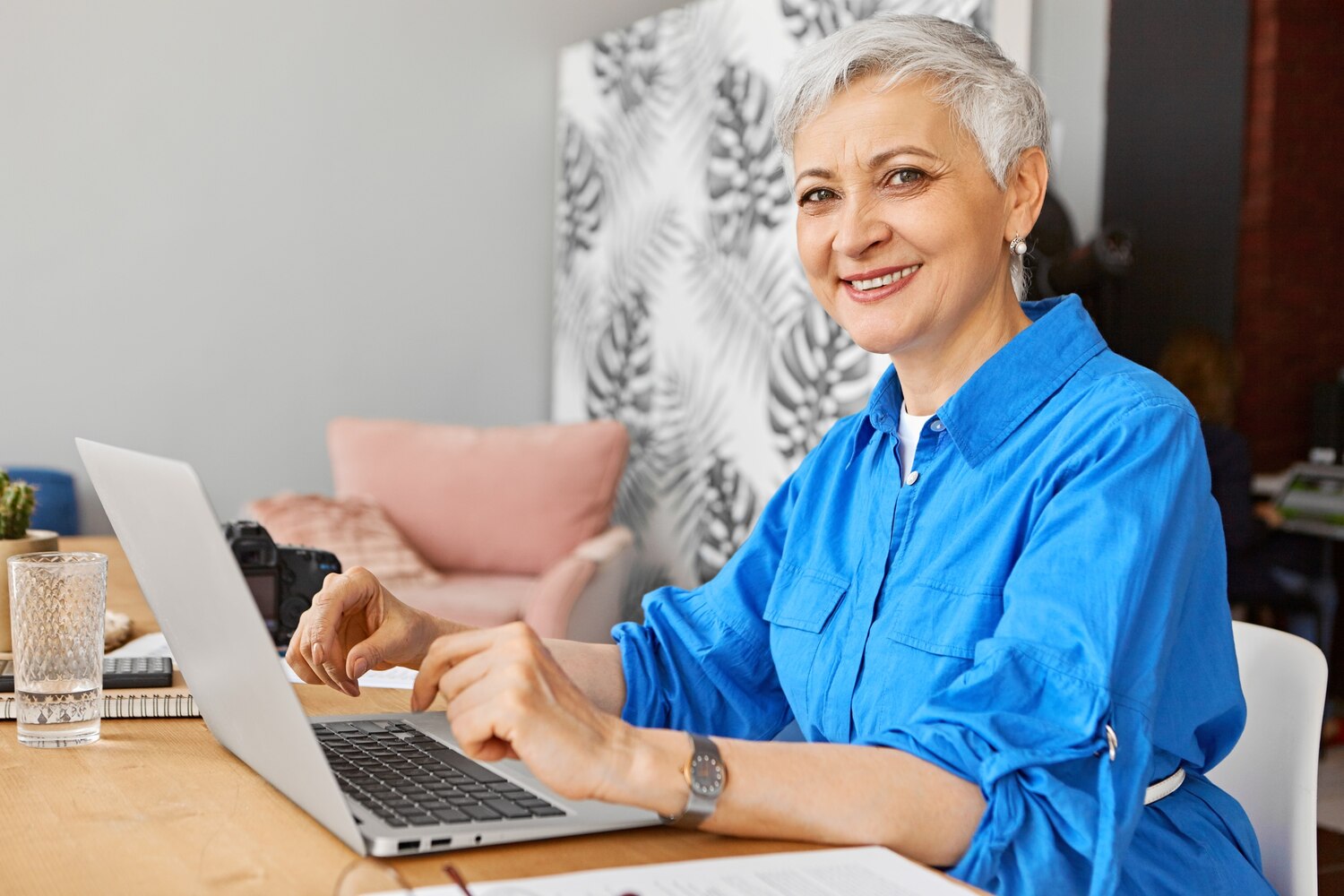 Mosolygó szakértő nő laptopon dolgozik az otthoni irodájában