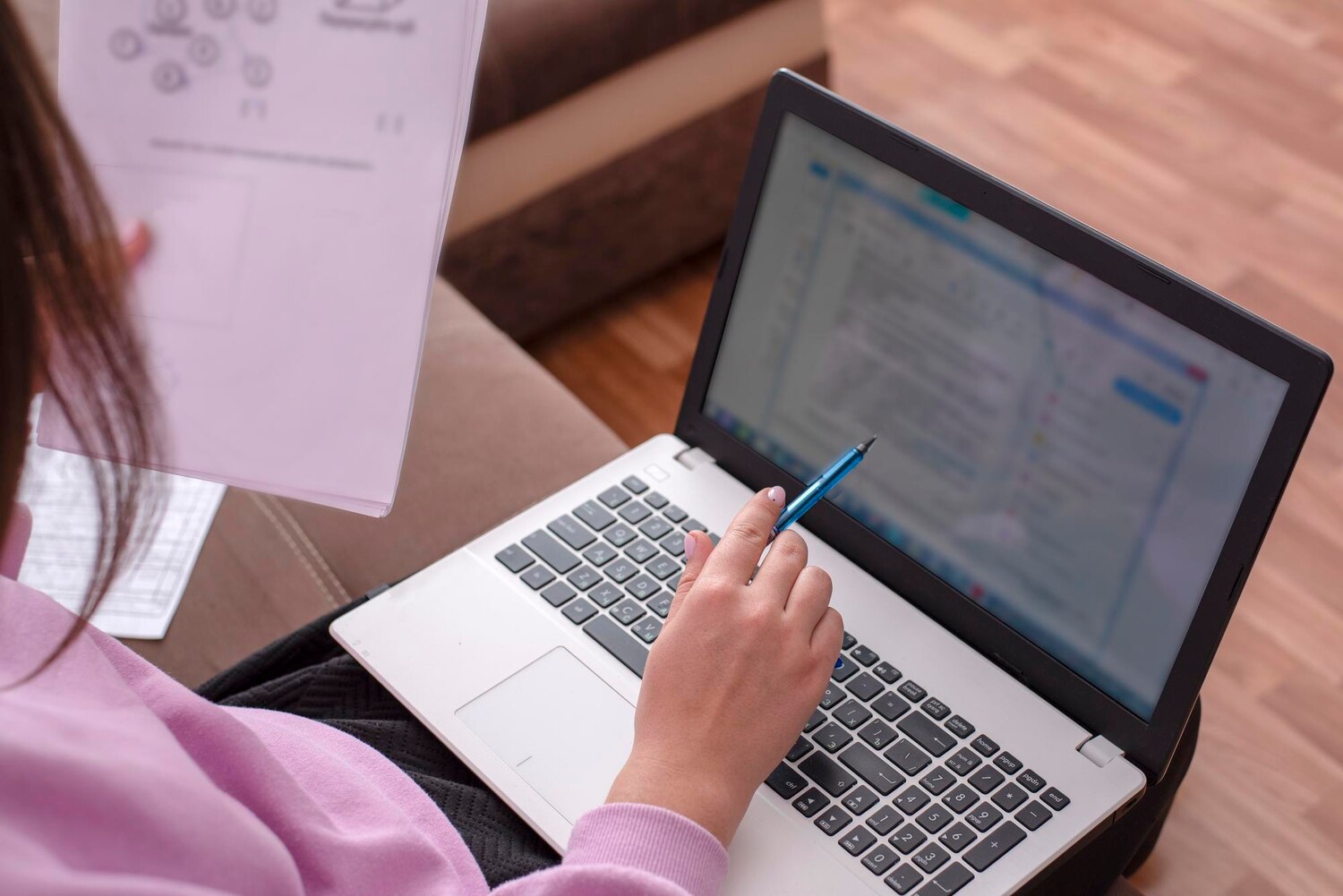 Nő tollal a kezében ellenőriz egy szöveget a laptopja képernyőjén