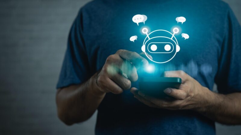 Okostelefont használó férfi felett megjelenő digitális mesterséges intelligencia chatbot ikon.