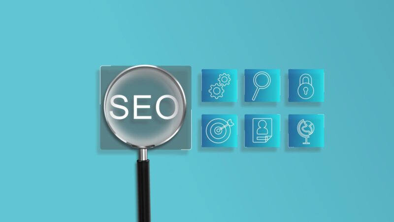 Nagyító a fehér SEO feliraton és kék digitális marketing ikonok világoskék háttér előtt.